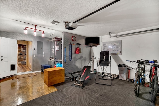 workout room featuring electric panel and a textured ceiling