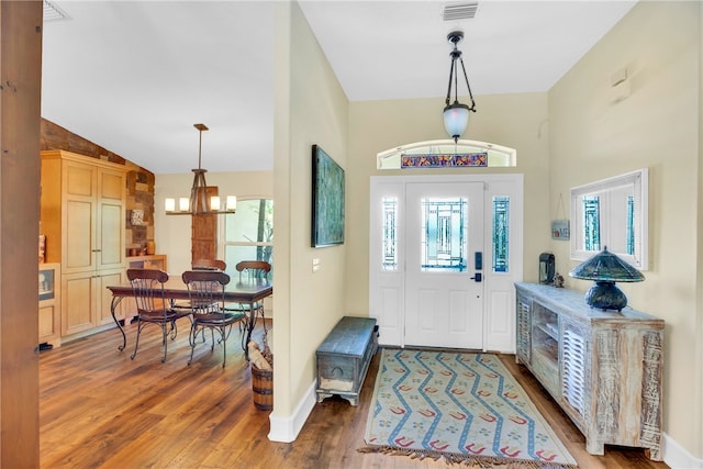 entryway featuring hardwood / wood-style floors, lofted ceiling, and a chandelier