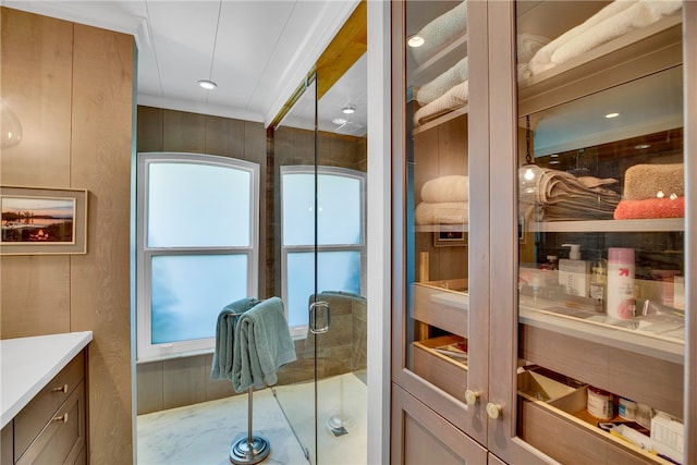 bathroom with a wealth of natural light, a shower with shower door, vanity, and wooden walls