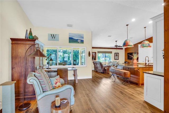 interior space featuring light hardwood / wood-style floors, ceiling fan, sink, and vaulted ceiling