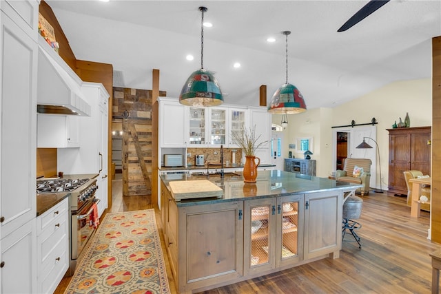 kitchen with a barn door, high end stainless steel range oven, a spacious island, and vaulted ceiling