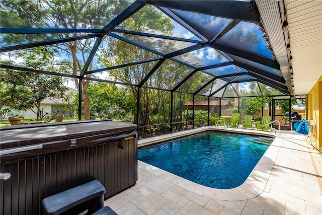 view of swimming pool featuring a patio, glass enclosure, and a hot tub