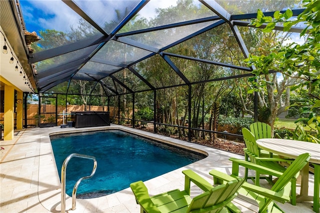 view of swimming pool with glass enclosure, a hot tub, and a patio area