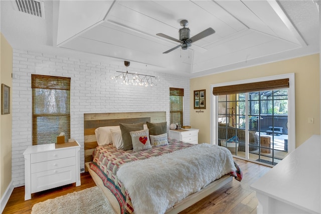 bedroom featuring access to outside, light hardwood / wood-style flooring, brick wall, and ceiling fan