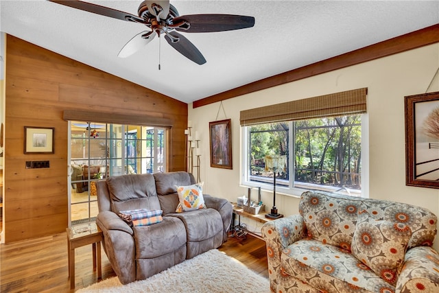 living room with wooden walls, hardwood / wood-style floors, vaulted ceiling, and plenty of natural light