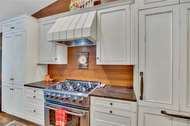 kitchen with high end stainless steel range oven, white cabinets, hardwood / wood-style floors, a textured ceiling, and premium range hood