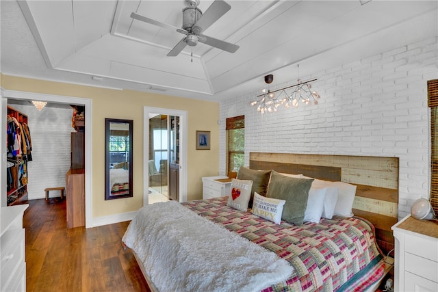 bedroom with dark wood-type flooring, ceiling fan, brick wall, and a closet