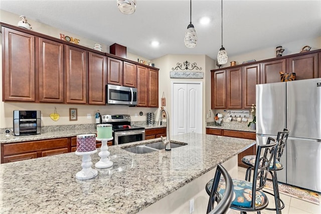 5744 Cahaba St, Port St Lucie, FL 34986 - kitchen featuring appliances with stainless steel finishes, light stone countertops, a kitchen bar, pendant lighting, and light tile patterned floors