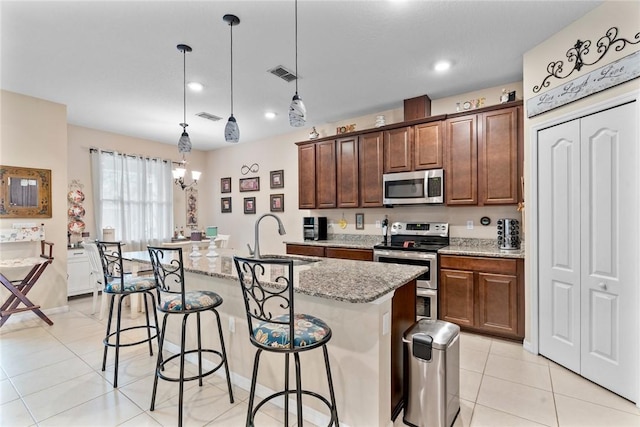 5744 Cahaba St, Port St Lucie, FL 34986 - kitchen with appliances with stainless steel finishes, a kitchen breakfast bar, light stone counters, a kitchen island with sink, and hanging light fixtures