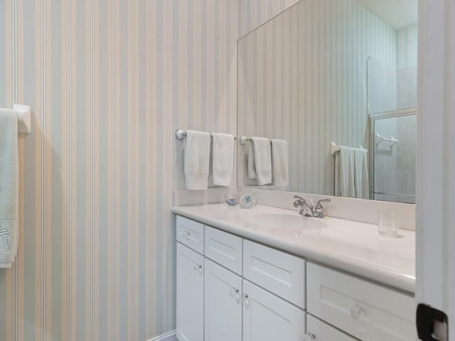 bathroom featuring a shower with door and vanity