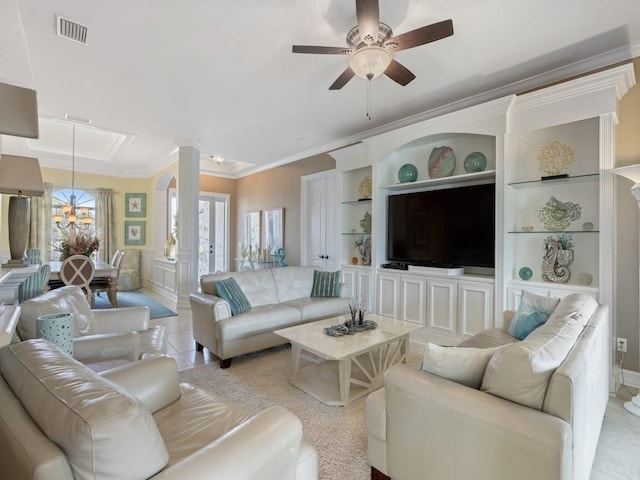 living room with built in shelves, ceiling fan with notable chandelier, and crown molding