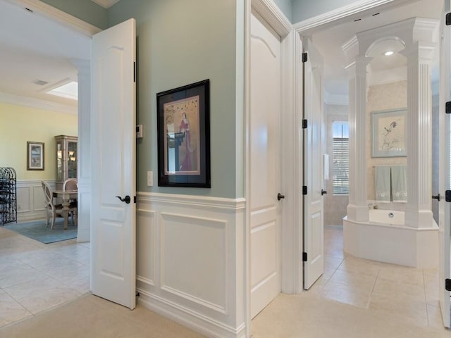 hall featuring ornamental molding, light tile patterned floors, and decorative columns