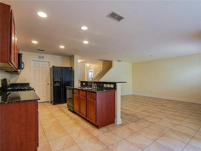 kitchen with dark stone countertops, sink, black appliances, and a kitchen island