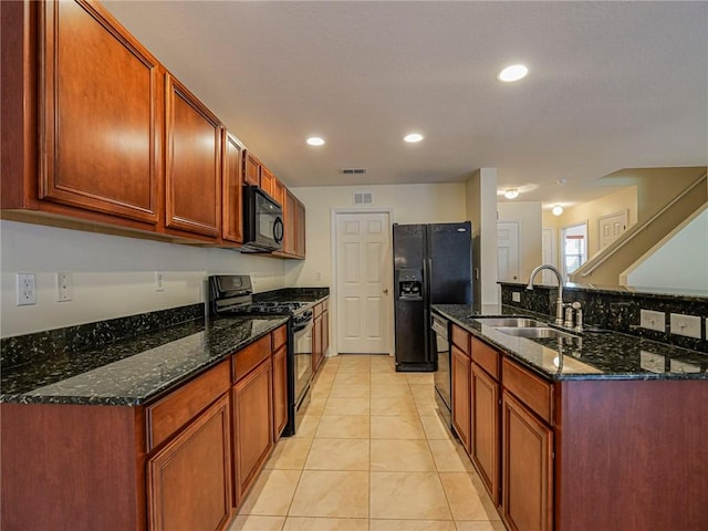 kitchen featuring sink, light tile patterned floors, black appliances, and dark stone counters