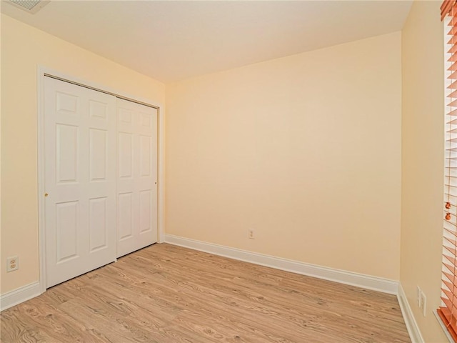 unfurnished bedroom featuring light hardwood / wood-style floors and a closet