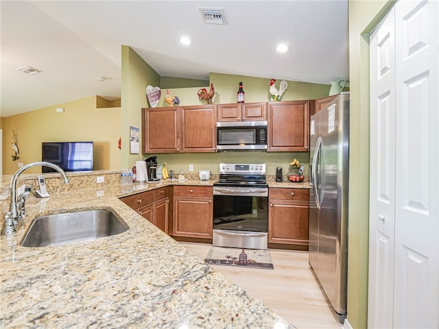 kitchen with light stone counters, stainless steel appliances, sink, light hardwood / wood-style floors, and lofted ceiling