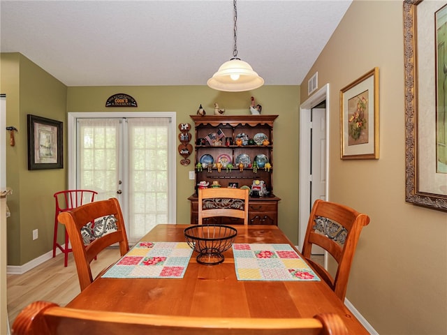 dining area with light hardwood / wood-style floors and french doors