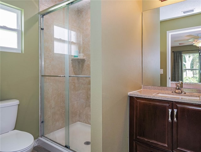 bathroom with a wealth of natural light, a shower with door, and toilet