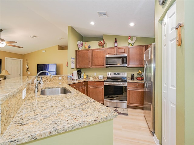 kitchen featuring stainless steel appliances, light hardwood / wood-style floors, sink, kitchen peninsula, and vaulted ceiling