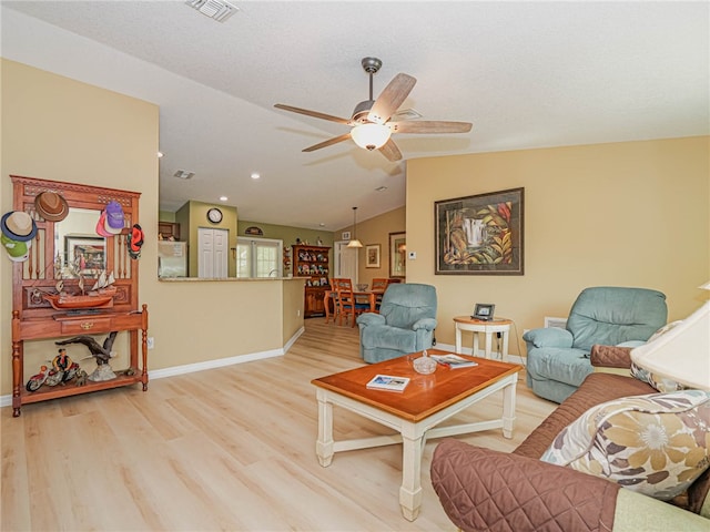 living room with light hardwood / wood-style floors, ceiling fan, and vaulted ceiling