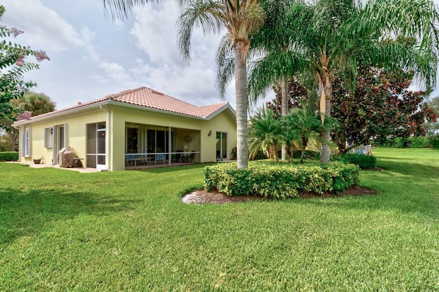 rear view of house with a lawn and a sunroom