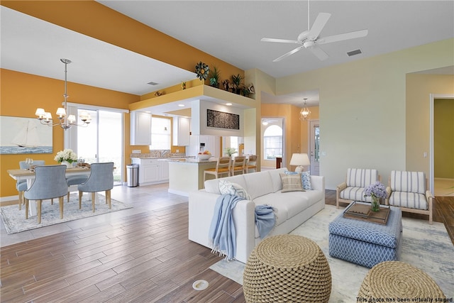 living room featuring ceiling fan with notable chandelier and light hardwood / wood-style floors