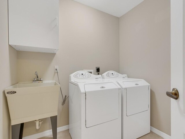 washroom with a sink, baseboards, cabinet space, and washer and dryer