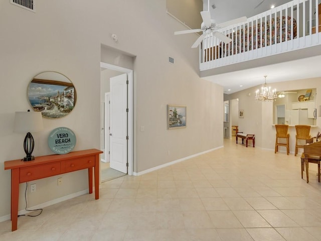 interior space with baseboards, a high ceiling, ceiling fan with notable chandelier, and visible vents