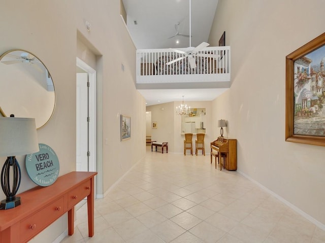 foyer entrance with light tile patterned floors, baseboards, a high ceiling, and ceiling fan with notable chandelier