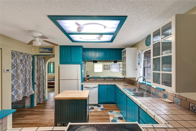 kitchen with a center island, sink, blue cabinetry, light hardwood / wood-style flooring, and white appliances