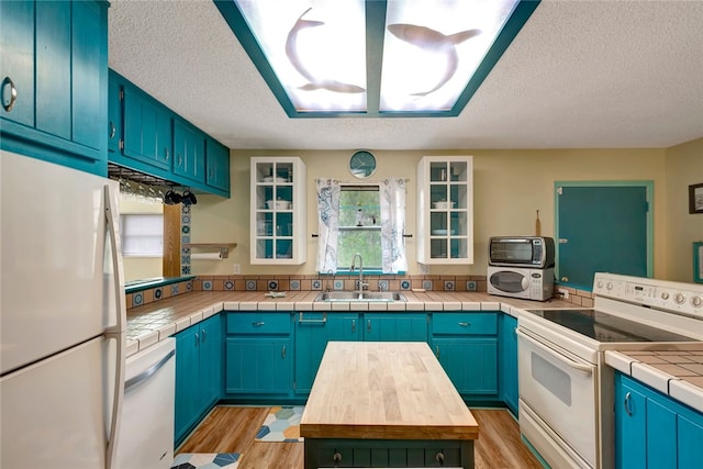 kitchen with blue cabinetry, white appliances, sink, and light hardwood / wood-style flooring