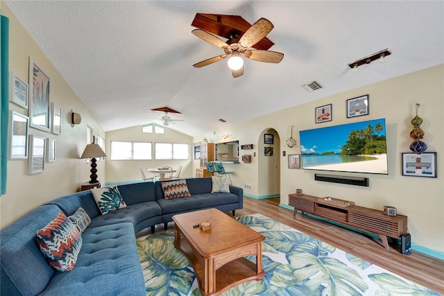 living room featuring a textured ceiling, vaulted ceiling, ceiling fan, and light hardwood / wood-style flooring