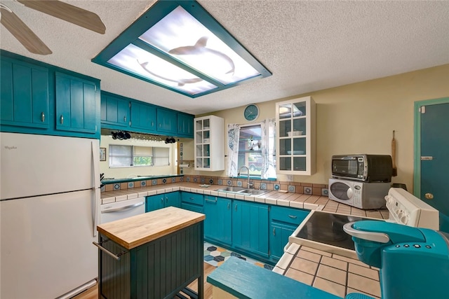 kitchen featuring a center island, a textured ceiling, sink, blue cabinetry, and white appliances