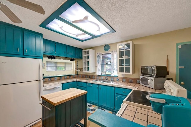 1514 Crowberry Ln, Sebastian, FL 32958 - kitchen with white appliances, a textured ceiling, wooden counters, glass insert cabinets, and blue cabinetry