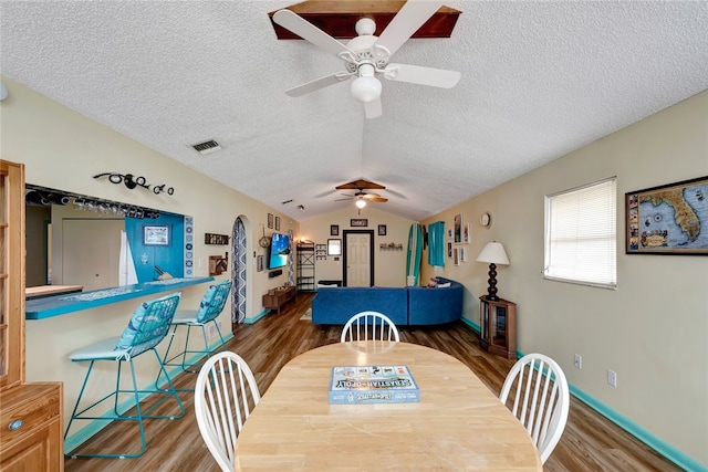 dining area with a textured ceiling, dark hardwood / wood-style flooring, lofted ceiling, and ceiling fan