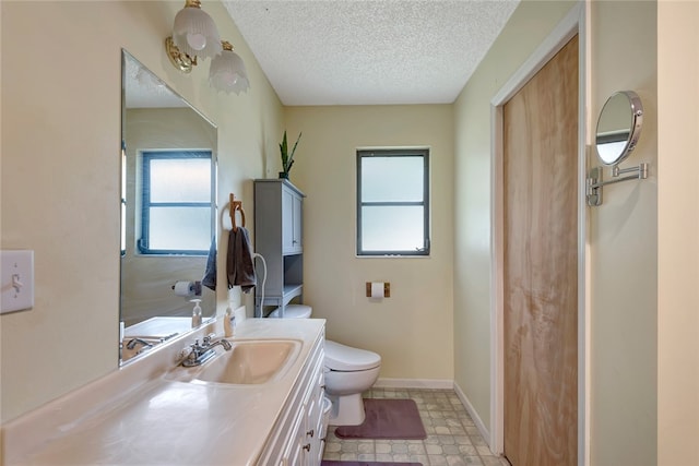 bathroom featuring a wealth of natural light, vanity, toilet, and a textured ceiling