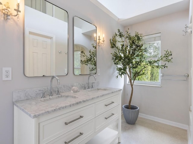 bathroom featuring a sink, baseboards, and double vanity