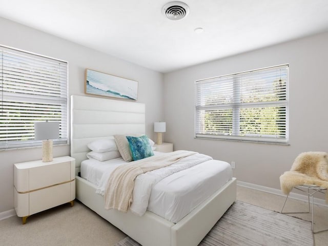 bedroom with light carpet, visible vents, and baseboards