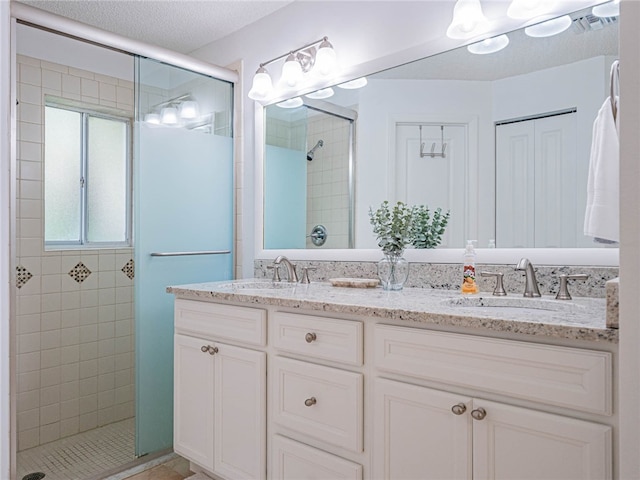 bathroom with vanity, a textured ceiling, and a shower with door