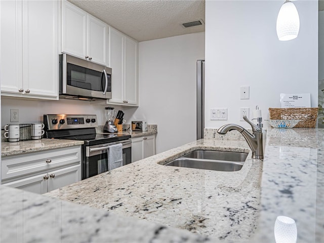 kitchen with stainless steel appliances, white cabinetry, sink, and light stone counters