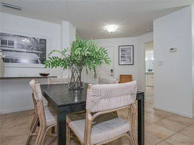 tiled dining room with a textured ceiling