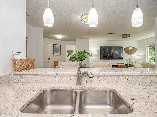 kitchen featuring pendant lighting, sink, and light stone counters