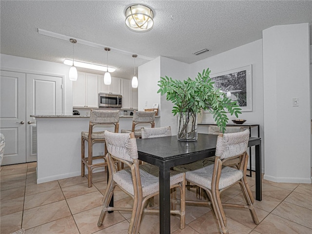 tiled dining room with a textured ceiling