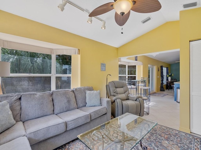 living room with lofted ceiling, rail lighting, ceiling fan, and light tile patterned flooring