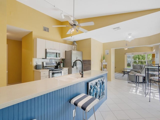 kitchen with sink, a breakfast bar area, tasteful backsplash, appliances with stainless steel finishes, and white cabinets