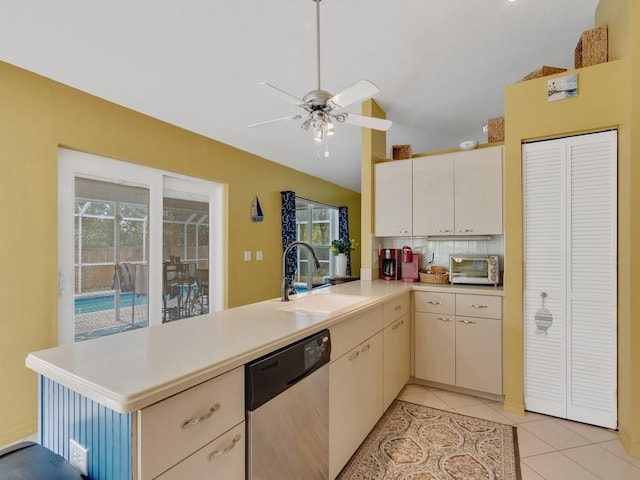 kitchen with vaulted ceiling, sink, stainless steel dishwasher, light tile patterned floors, and kitchen peninsula