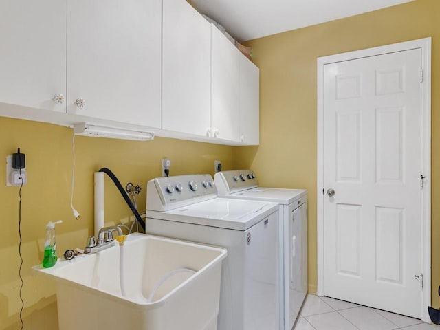 clothes washing area featuring cabinets, sink, washing machine and dryer, and light tile patterned floors