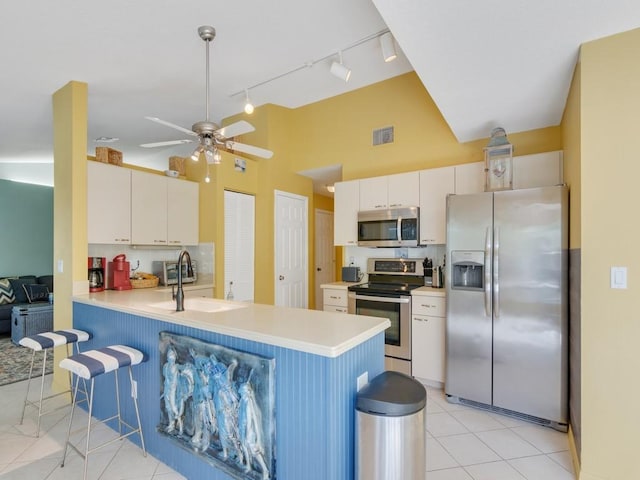 kitchen with sink, a breakfast bar area, white cabinets, kitchen peninsula, and stainless steel appliances