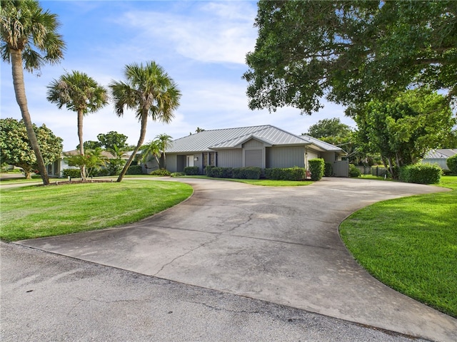 675 Colonial Dr, Vero Beach, FL 32962 - single story home featuring curved driveway, a front lawn, a metal roof, and a standing seam roof