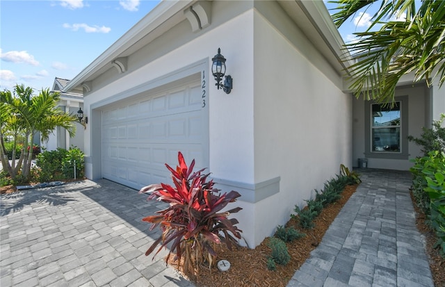1223 Harper Way Unit 009, Vero Beach, FL 32960 - view of home's exterior featuring stucco siding, an attached garage, and decorative driveway